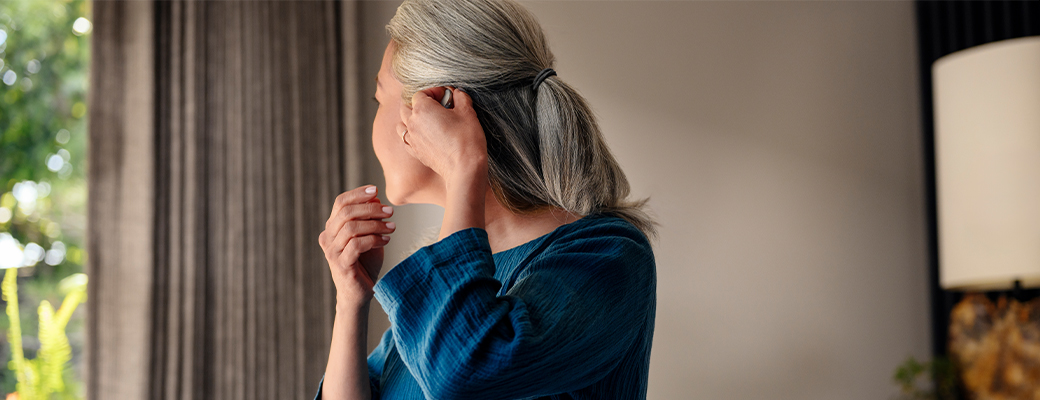 Image of woman putting on her hearing aid